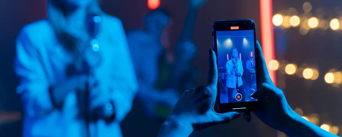 Person taking picture of a singer with a phone